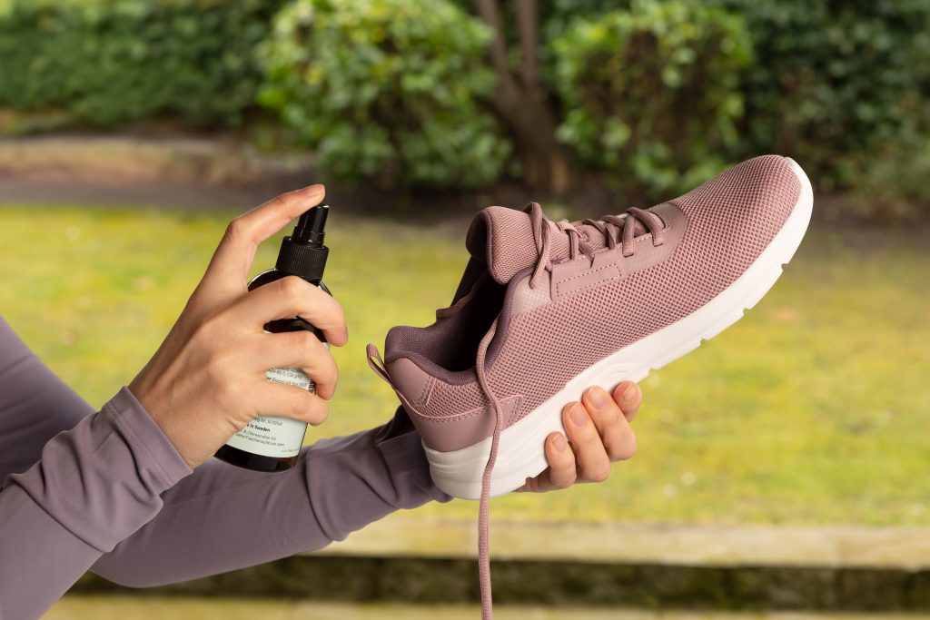 Hände mit Myfungar® Desinfizierendem Schuhspray und Schuh: Das Schuhspray beseitigt 99,9 % aller Bakterien und entfernt Pilzsporen.